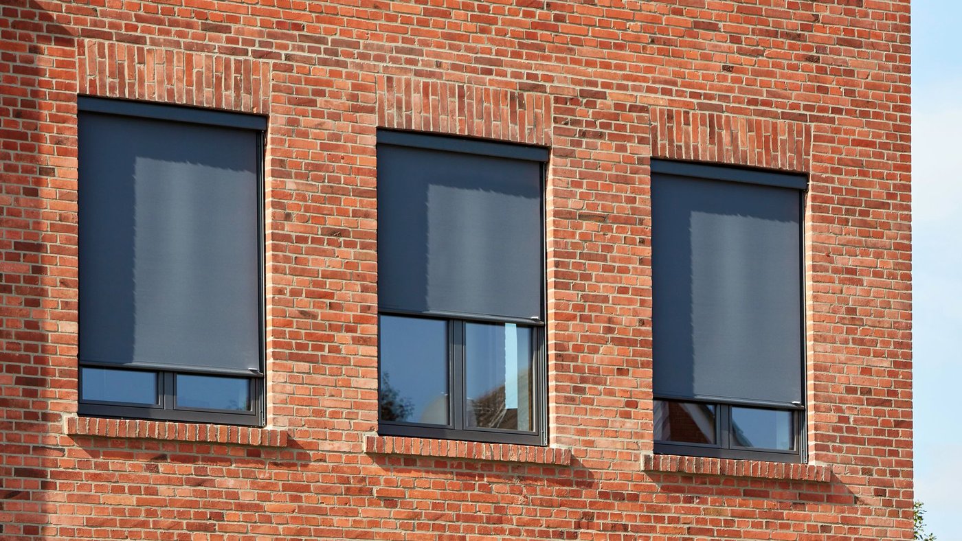 Murstensbygning med lodrette Markilux 620 screenmarkiser med grå dug