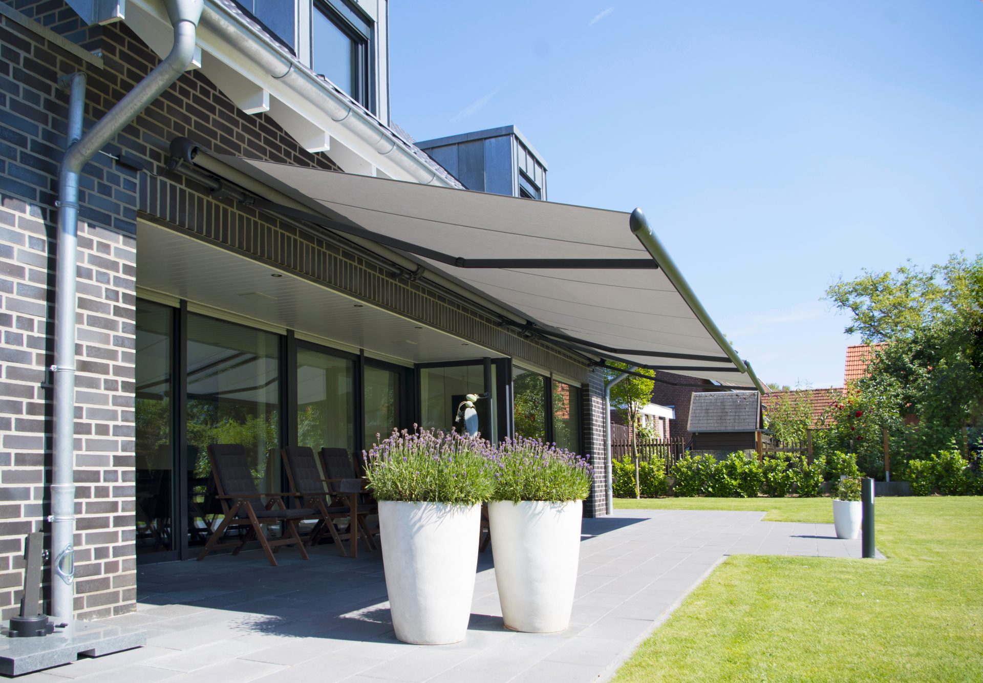 Grå Markilux 1600 halvkassettemarkise med grå dug over en terrasse på et fritliggende hus