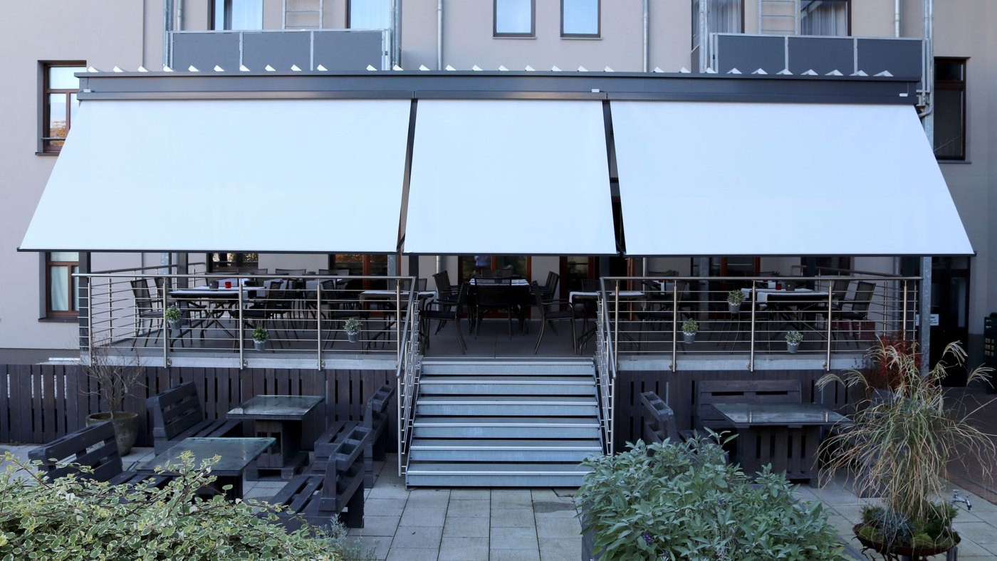 Tre faldarms-kassettemarkiser Markilux 730 med hvid dug monteret på en veranda