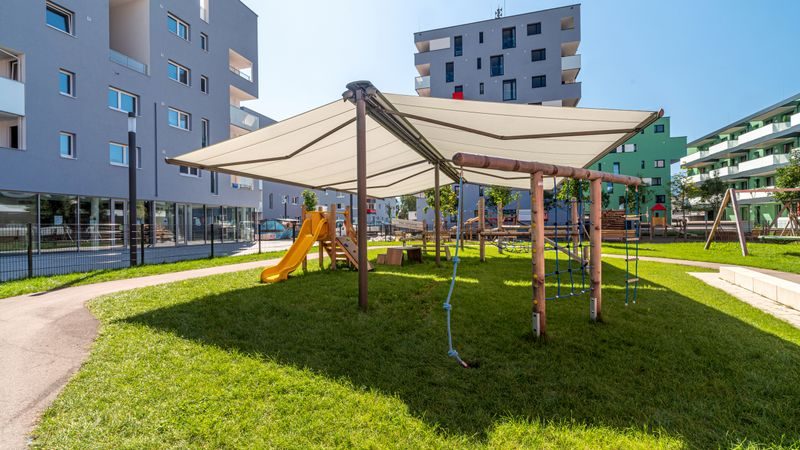 Børnehavebørn sidder på terrassen under en dobbeltsidet markise